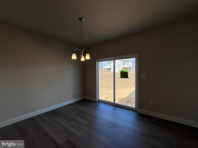 unfurnished dining area featuring an inviting chandelier, dark wood-style floors, and baseboards