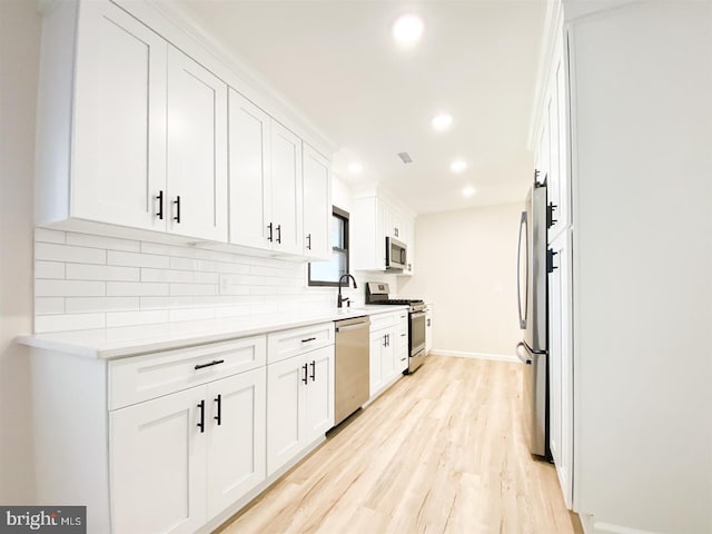 kitchen featuring white cabinets, tasteful backsplash, sink, light hardwood / wood-style floors, and stainless steel appliances