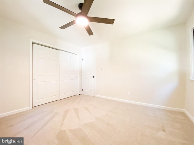 unfurnished bedroom featuring light carpet, a closet, and ceiling fan