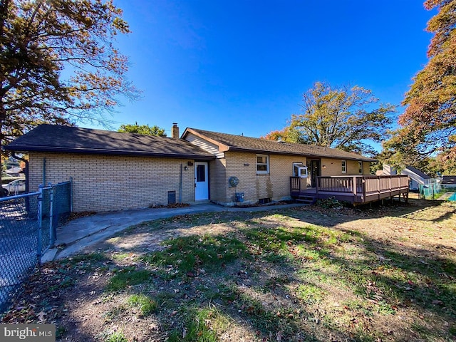 rear view of house featuring a deck and a lawn