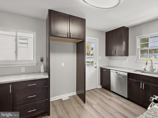 kitchen featuring light stone counters, backsplash, stainless steel dishwasher, light hardwood / wood-style floors, and sink