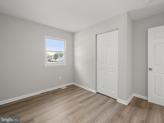 unfurnished bedroom with a closet and light wood-type flooring