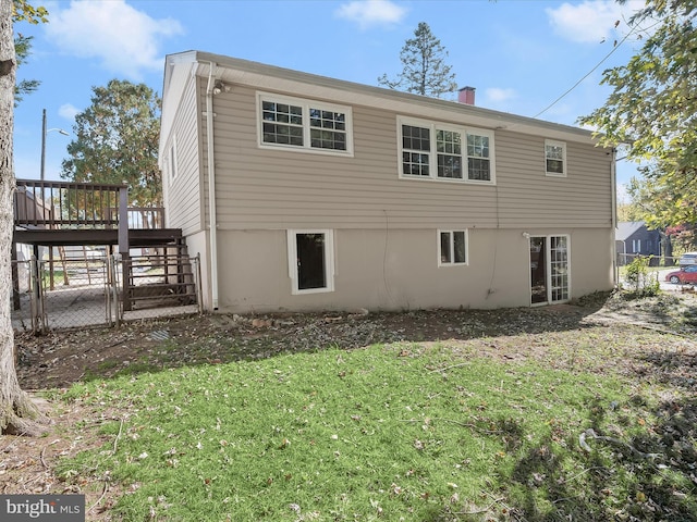 back of property with a deck and a lawn