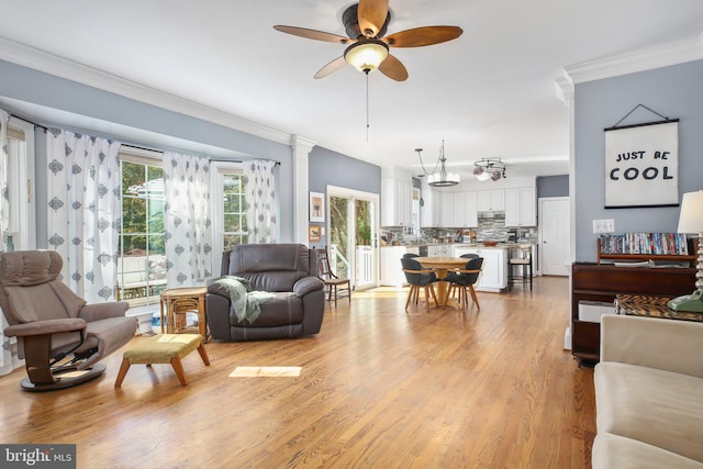 living room with ornate columns, ceiling fan, ornamental molding, and light wood-type flooring