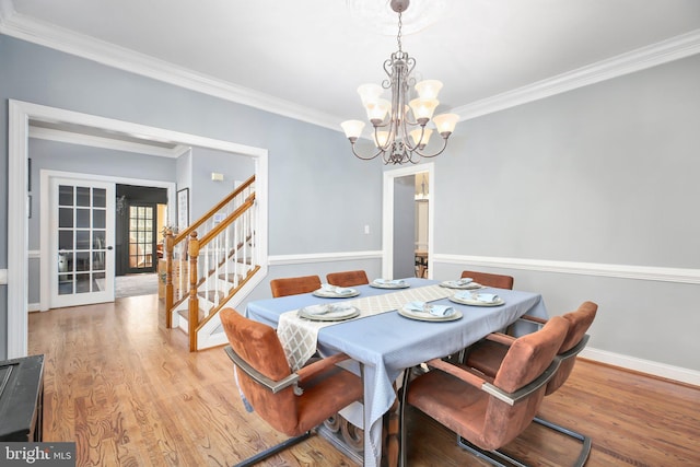 dining space featuring a notable chandelier, ornamental molding, hardwood / wood-style flooring, and french doors