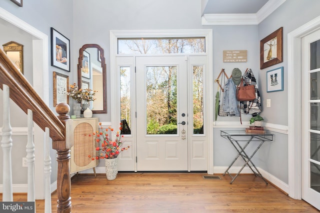 entryway with crown molding, light wood-type flooring, and plenty of natural light