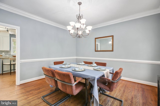 dining area featuring hardwood / wood-style floors, crown molding, and an inviting chandelier