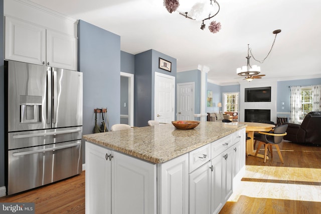 kitchen with a kitchen island, stainless steel fridge, crown molding, light wood-type flooring, and white cabinetry