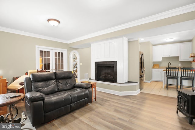 living room featuring light hardwood / wood-style flooring, ornamental molding, and french doors