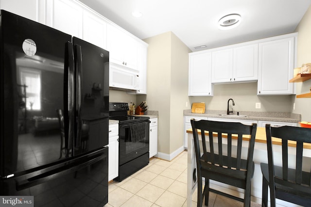 kitchen with sink, black appliances, white cabinets, and light tile patterned flooring