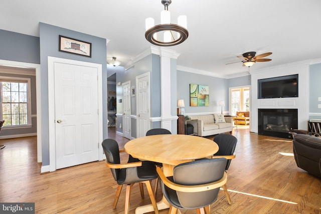 dining space with light hardwood / wood-style floors, crown molding, decorative columns, and a wealth of natural light