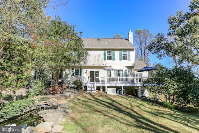 rear view of house featuring a wooden deck and a lawn