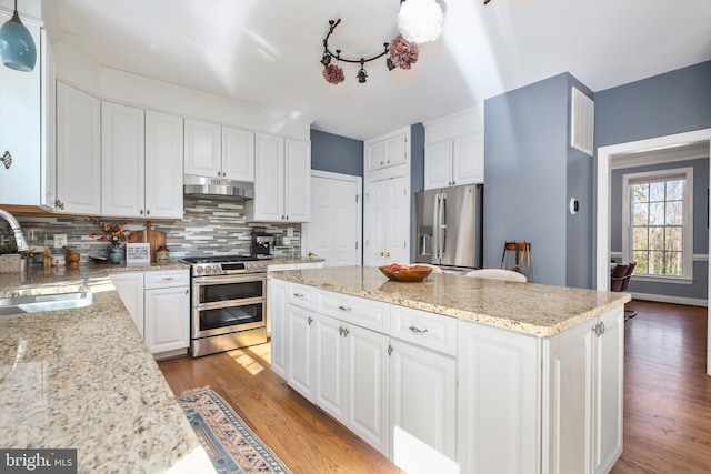 kitchen with light stone countertops, sink, white cabinetry, stainless steel appliances, and light hardwood / wood-style flooring