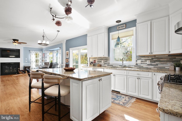 kitchen featuring white cabinetry, light stone counters, and pendant lighting