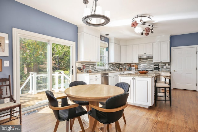 kitchen with a kitchen island, white cabinetry, pendant lighting, and a healthy amount of sunlight