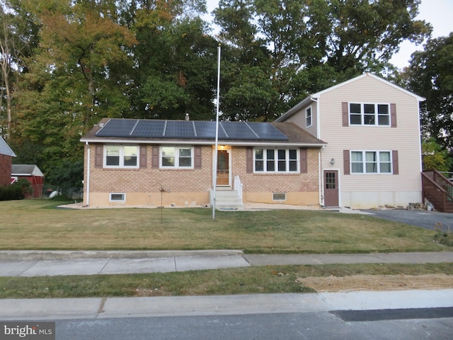 view of front of house with a front lawn and solar panels