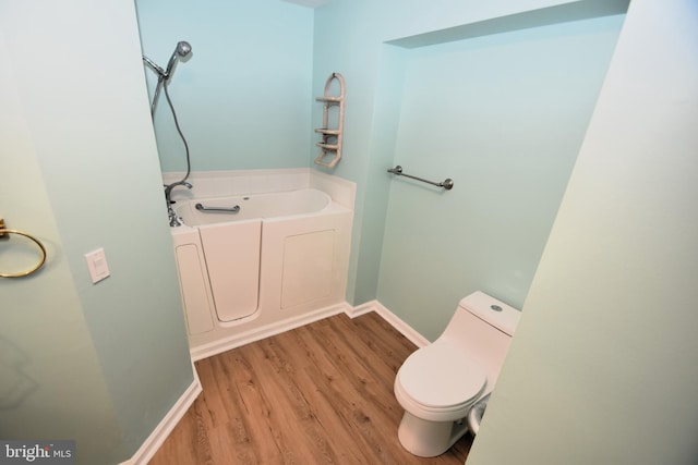 bathroom featuring a bath, toilet, and hardwood / wood-style flooring