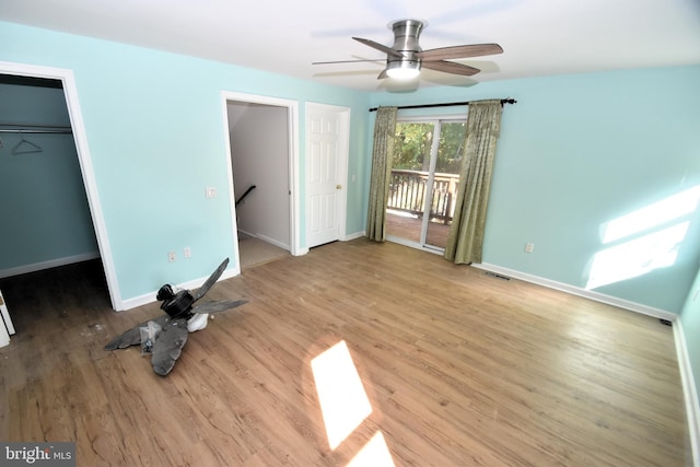 unfurnished bedroom with ceiling fan, a spacious closet, access to exterior, light hardwood / wood-style floors, and a closet