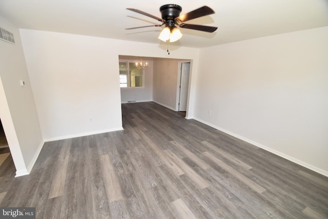 spare room with ceiling fan with notable chandelier and dark hardwood / wood-style floors