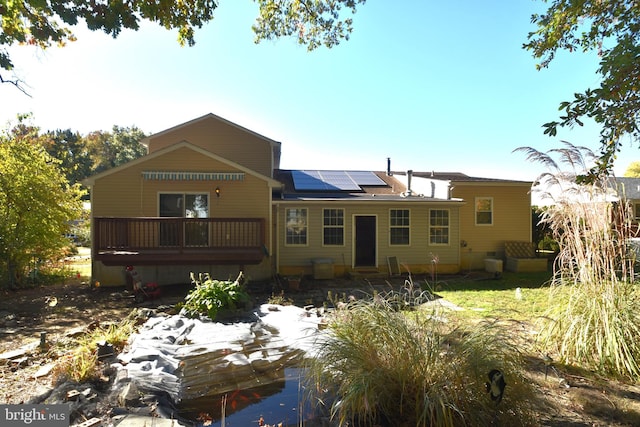 rear view of property with solar panels and a wooden deck