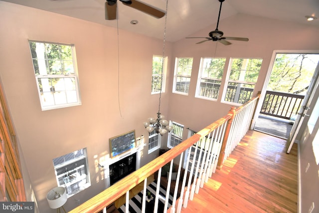 corridor featuring hardwood / wood-style floors, vaulted ceiling, and a chandelier