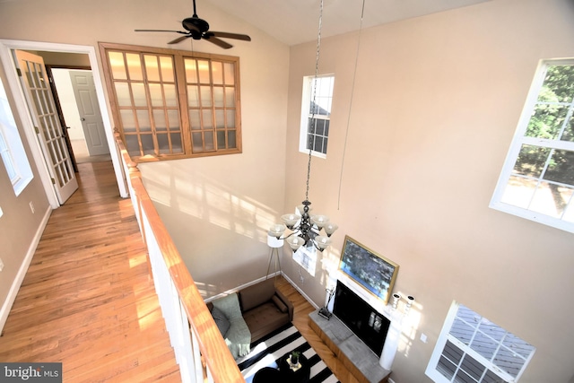 unfurnished living room featuring hardwood / wood-style flooring, ceiling fan with notable chandelier, and vaulted ceiling