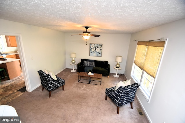 living room featuring light carpet, a textured ceiling, sink, and ceiling fan