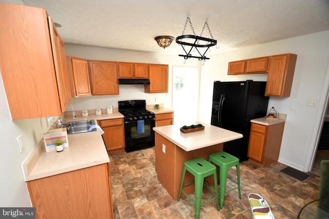 kitchen with a breakfast bar area, sink, black appliances, a center island, and a chandelier