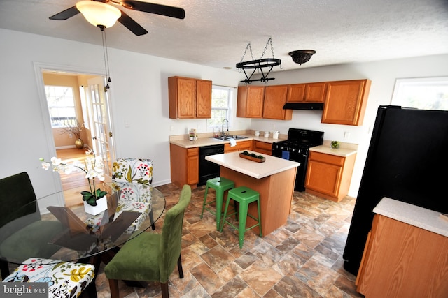 kitchen featuring a kitchen island, sink, black appliances, a kitchen bar, and ceiling fan