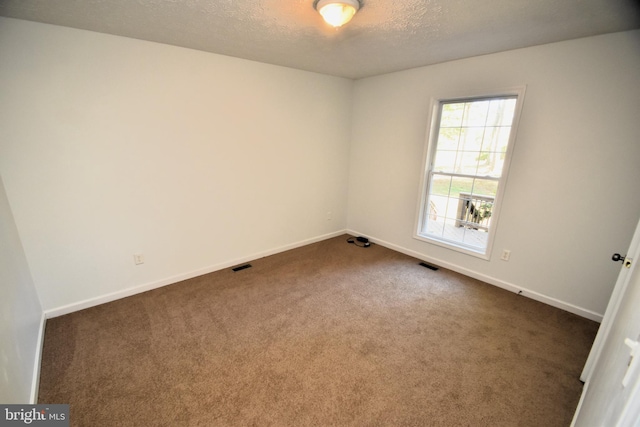 carpeted empty room featuring a textured ceiling