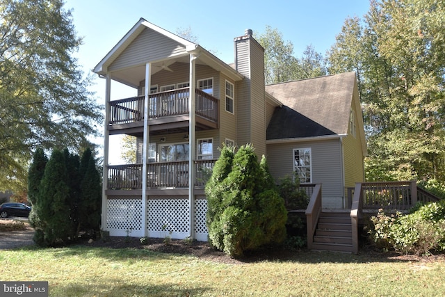 rear view of house featuring a wooden deck and a lawn