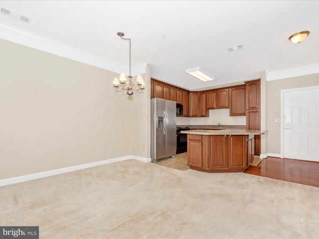 kitchen with hanging light fixtures, crown molding, black appliances, and a kitchen island