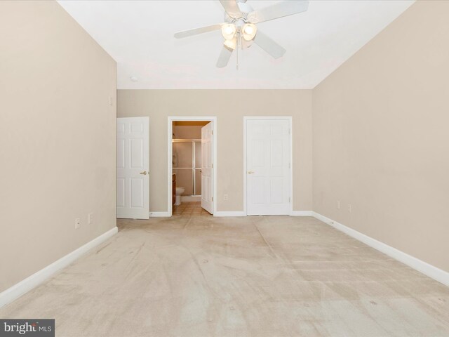 unfurnished bedroom with a spacious closet, light colored carpet, ceiling fan, and ensuite bath