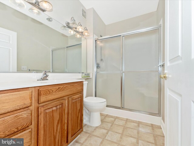 bathroom with a shower with door, vanity, and toilet