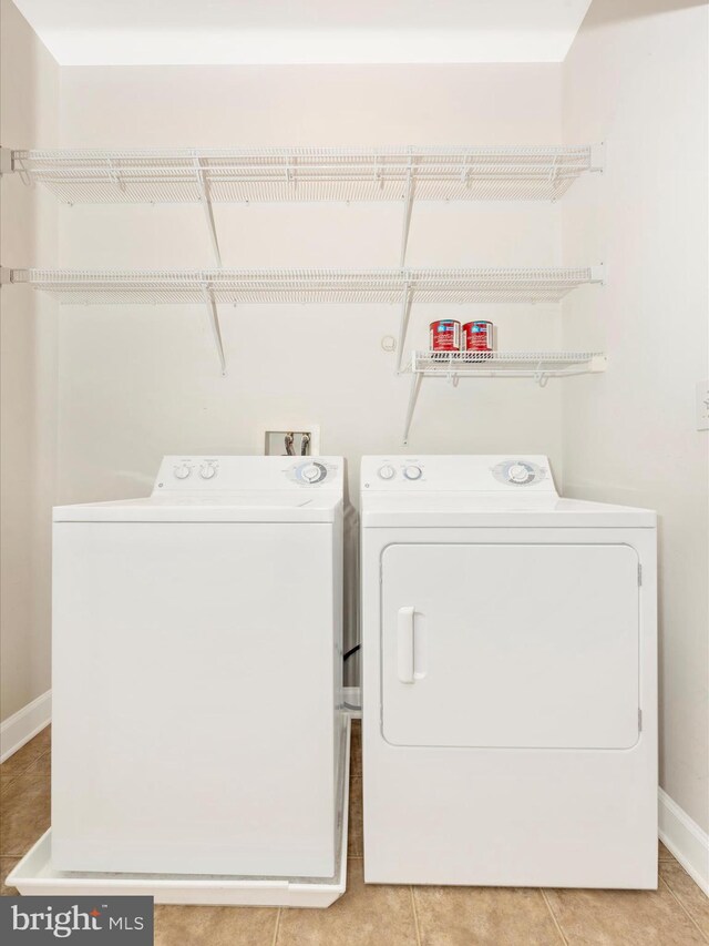 clothes washing area with washer and dryer and light tile patterned floors