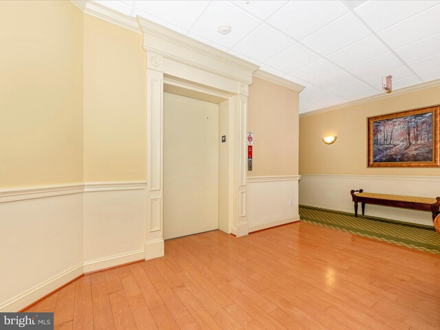 interior space featuring a paneled ceiling, hardwood / wood-style floors, and crown molding