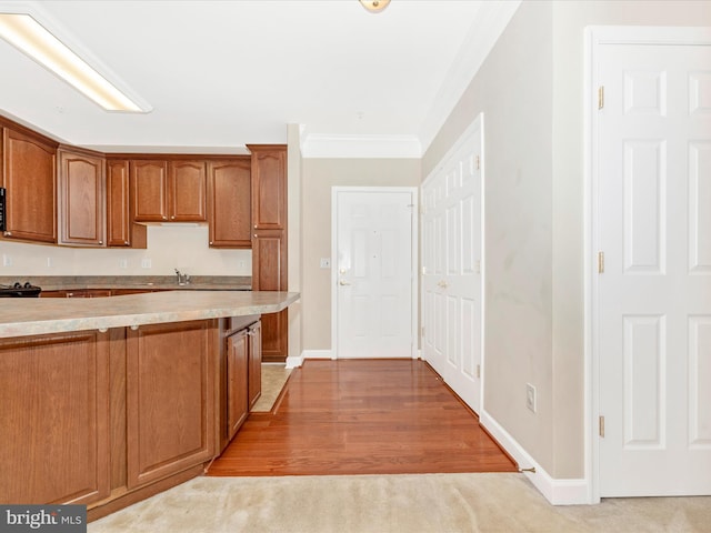 kitchen with black range oven, sink, light hardwood / wood-style flooring, and crown molding