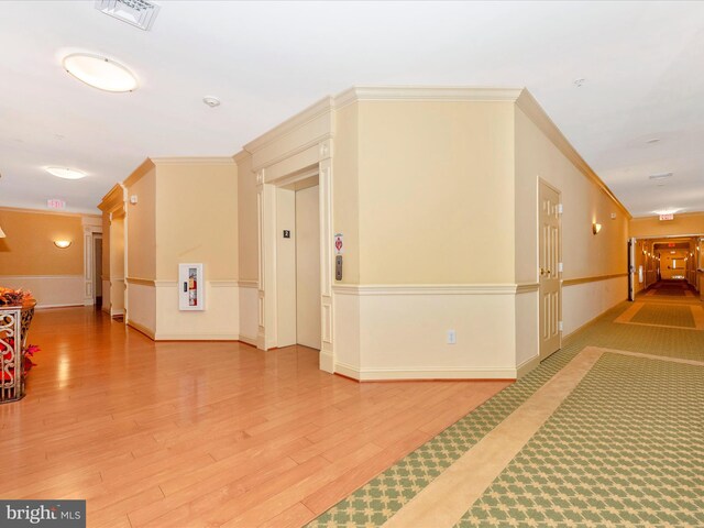 hall with elevator, hardwood / wood-style flooring, and ornamental molding