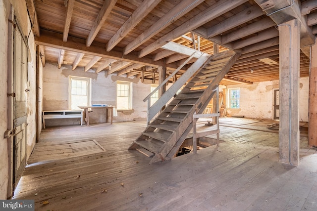 basement featuring plenty of natural light, wood ceiling, hardwood / wood-style flooring, and stairway