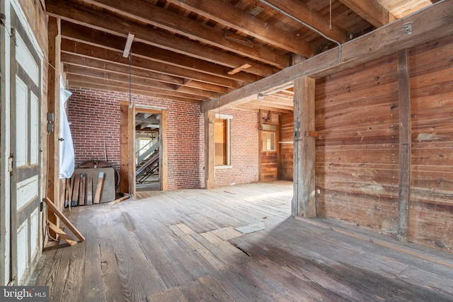 misc room featuring hardwood / wood-style flooring, wooden ceiling, brick wall, and wooden walls