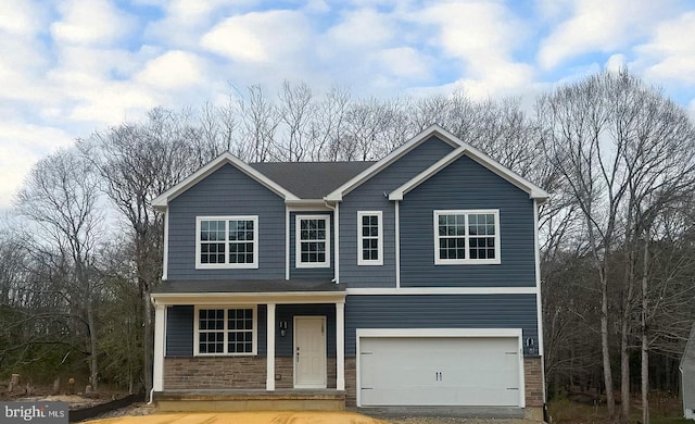 traditional-style house with an attached garage, driveway, stone siding, and covered porch