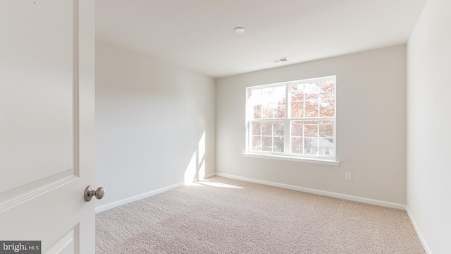 carpeted spare room with a wealth of natural light, visible vents, and baseboards