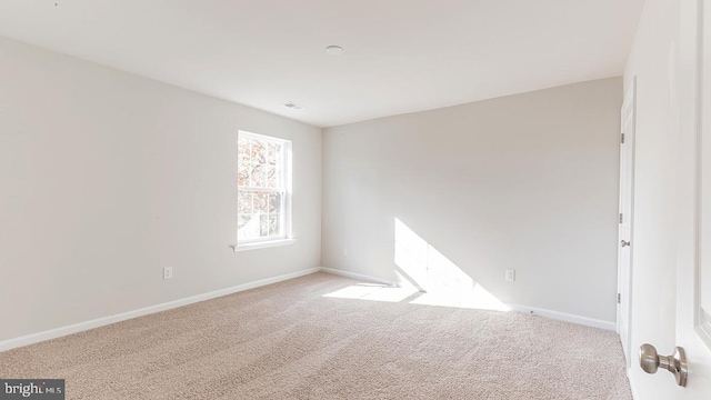 carpeted spare room with baseboards and visible vents