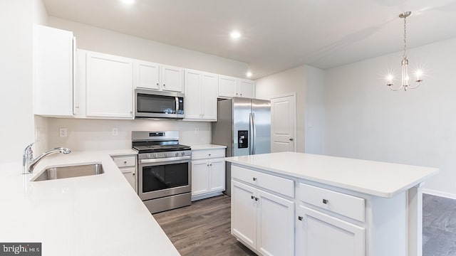 kitchen with sink, hanging light fixtures, stainless steel appliances, white cabinets, and dark wood-type flooring