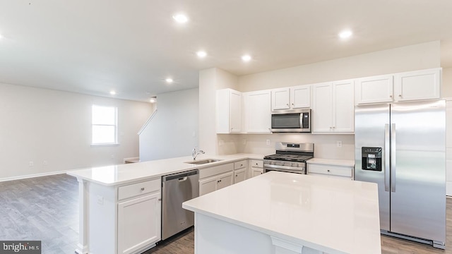 kitchen with appliances with stainless steel finishes, white cabinets, sink, and a kitchen island