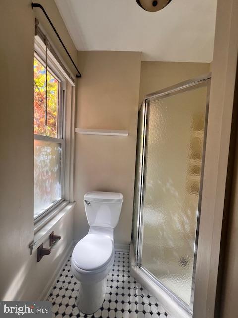 bathroom featuring an enclosed shower and toilet