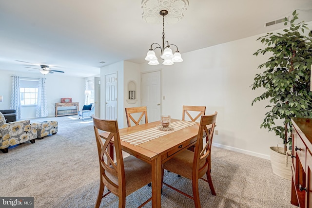 dining area featuring carpet and ceiling fan with notable chandelier