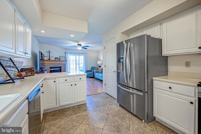 kitchen with kitchen peninsula, white cabinets, ceiling fan, light tile patterned flooring, and stainless steel appliances