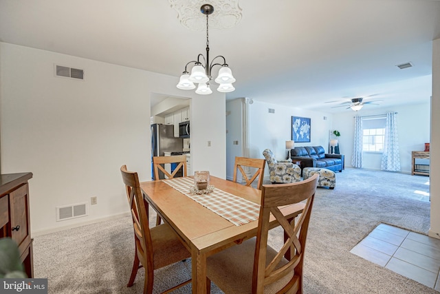 dining space featuring light colored carpet and ceiling fan with notable chandelier