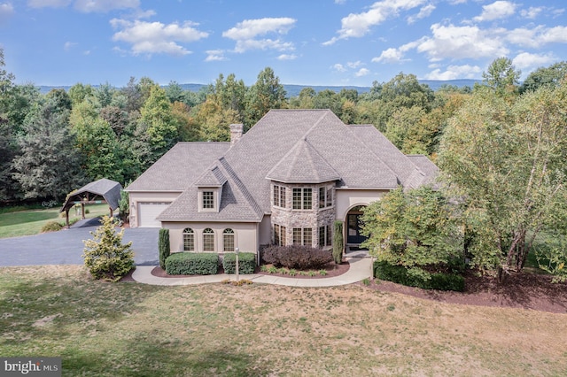 french provincial home featuring aphalt driveway, stucco siding, a chimney, and a front lawn